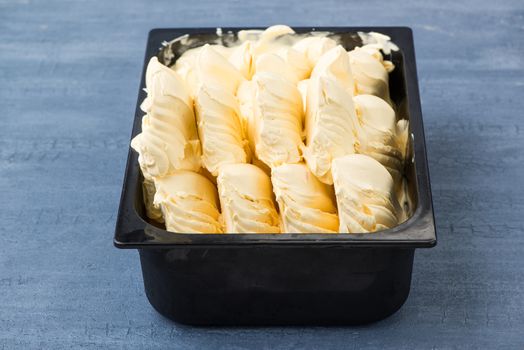 appetizing ice cream in a plastic container on a decorative blue background