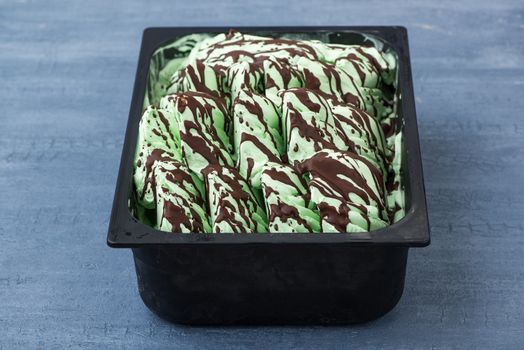 appetizing ice cream in a plastic container on a decorative blue background