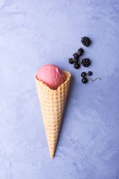 ice cream with berries in a waffle horn on an ornamental purple background, top view