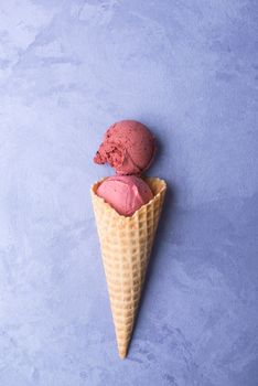 ice cream in a waffle horn on an ornamental purple background, top view