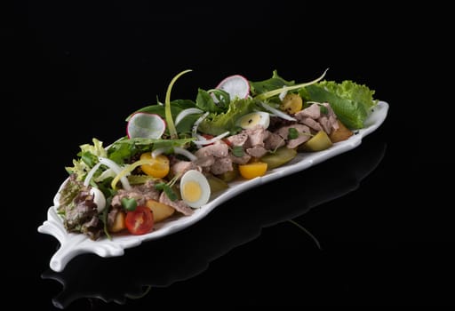 meat salad with eggs on a black background, isolated