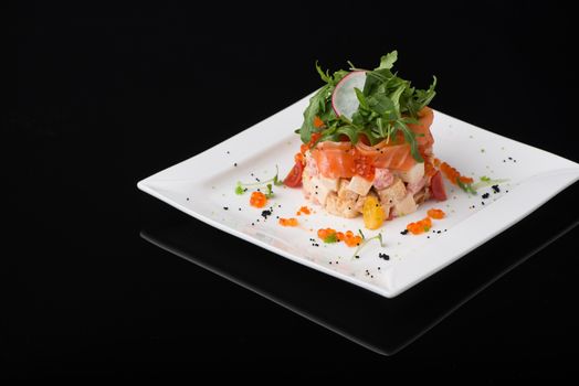salad in a white square plate on a black background