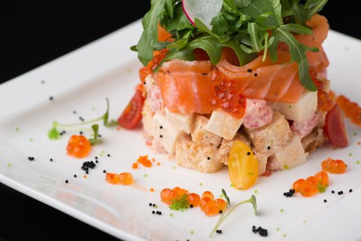 salad in a white square plate on a black background