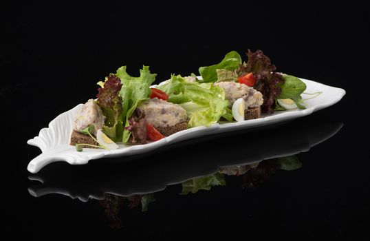 meat salad with eggs on a black background, isolated