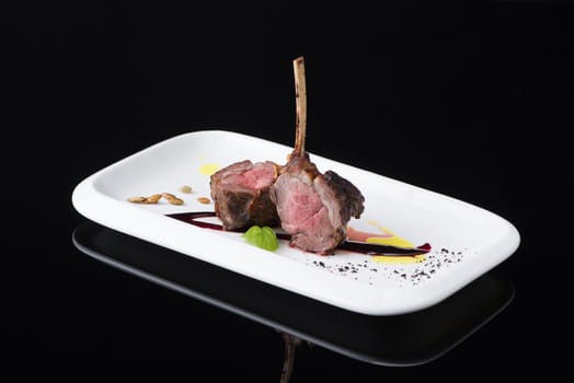 roasted meat in a plate on a black background, isolated