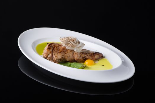 dish of meat with egg in a plate, on a black background, isolated