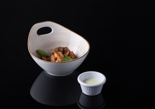 dish of meat in a bowl on a black background, isolated