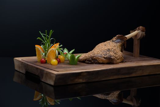 roasted meat with sesame seeds on a wooden tray, on a dark background