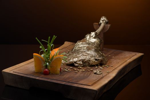 roast meat with bone in gold leaf on a wooden tray