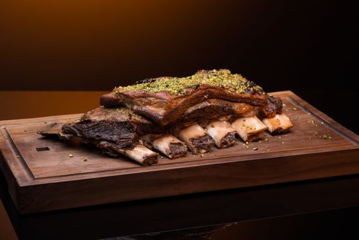 roast meat with bone on a wooden tray, dark background, isolated