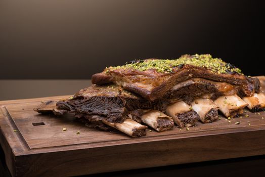 roast meat with bone on a wooden tray, dark background, isolated