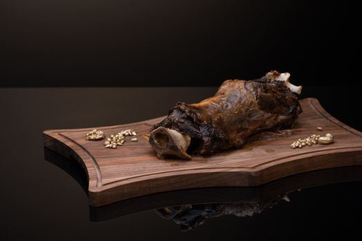 roast meat with bone on a wooden tray, dark background, isolated
