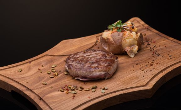 roast meat on a wooden tray, dark background, isolated