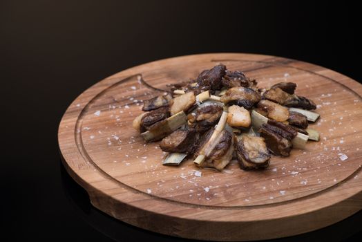 roast meat with bone on a wooden tray, dark background, isolated