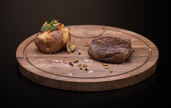 roast meat on a wooden tray, dark background, isolated