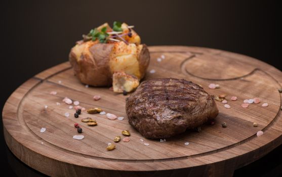 roast meat on a wooden tray, dark background, isolated