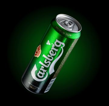 Almaty, Kazakhstan - October 11, 2019: can of beer Carlsberg with drops of water in a green background with illumination. Advertising a brand of beer