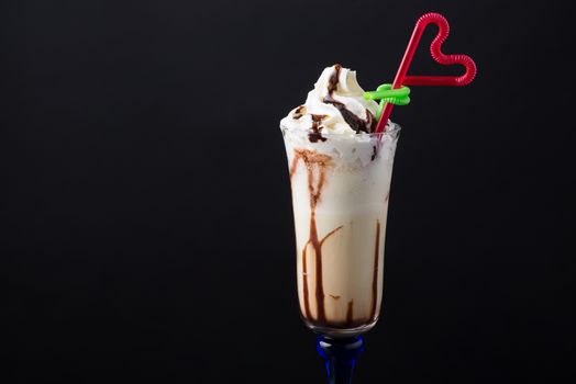 chocolate fruit cocktail ice cream with straw on black background, isolated. summer tropical smoothie
