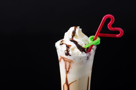 chocolate fruit cocktail ice cream with straw on black background, isolated. summer tropical smoothie