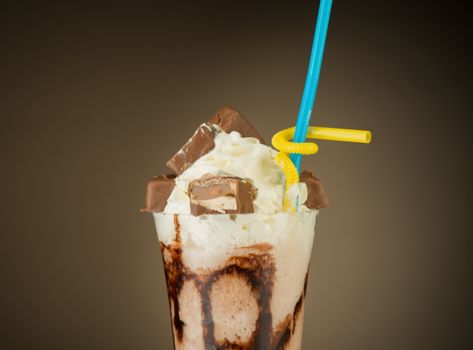 chocolate fruit cocktail ice cream with straw on brown backlit background, isolated. summer tropical smoothie