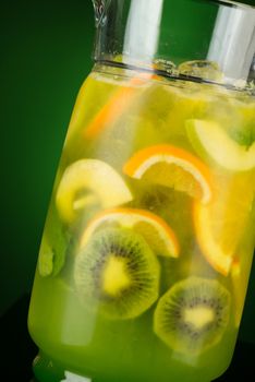 cold drink of citrus in a decanter on a green background. summer tropical juice