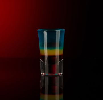 mixed alcoholic liquor in a shot glass isolated on a red background with backlighting