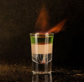 flaming cocktail with cinnamon in a shot glass on a black background, isolated