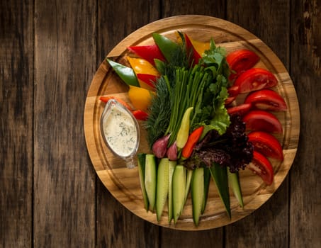fresh sliced pieces of vegetables on a round tray. assortment of vegetables on a wooden surface, top view