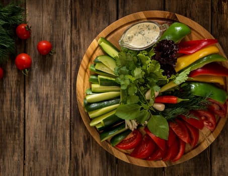 fresh sliced pieces of vegetables on a round tray. assortment of vegetables on a wooden surface, top view