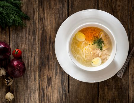 soup with noodles and quail eggs on wooden surface, view from above