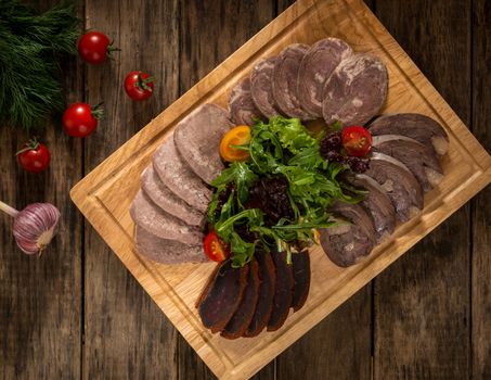 sliced meatloaf on a wooden tray and is decorated with vegetables, top view