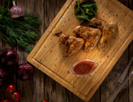 fried chicken wings decorated with vegetables on a wooden tray, top view