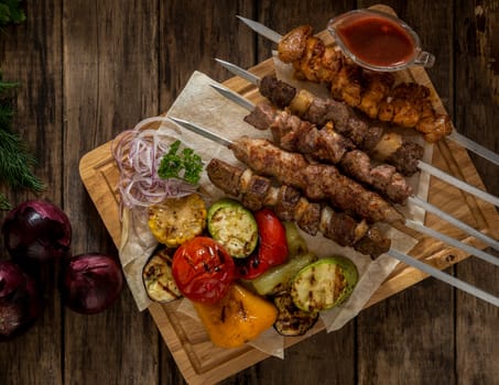 grilled meat with vegetables on skewers on wooden boards, top view