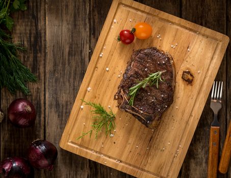 succulent meat adorned with tomato and onion on wooden background, top view