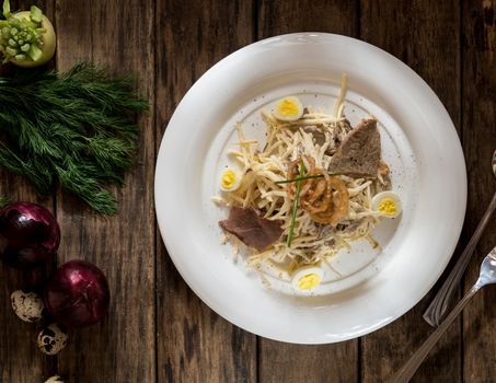 a dish of meat and cheese, decorated with quail eggs and onion on wooden boards, top view