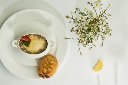 mushroom soup with lemon slices on a white surface with the shadow of wine glasses