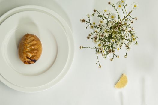 pies and chamomile flowers on a white surface with a shadow from the wine glasses