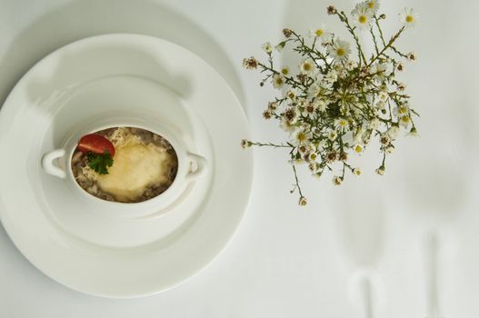 mushroom soup and chamomile flowers on a white surface with a shadow from the wine glasses