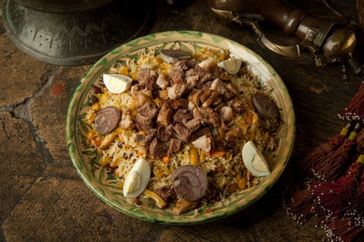 oriental dishes on decorative old tiles. pilaf and pitcher on decorative old paving stones