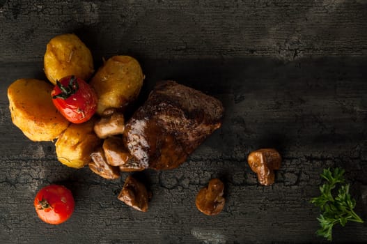 close-up fried meat with potatoes on a wooden old board. fried meat with potatoes and mushrooms on a wooden old surface