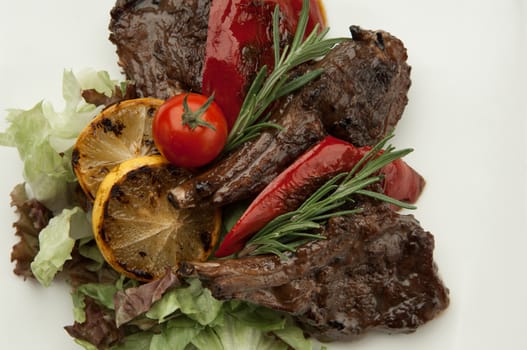 fried meat with tomato and lemon on white background closeup. roasted meat ribs close-up on a light background