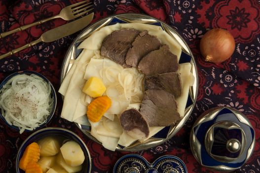 oriental dish of boiled meat and dough on a tablecloth