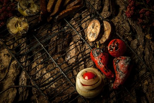 roasted vegetables and apples on a grill on a background of tree bark