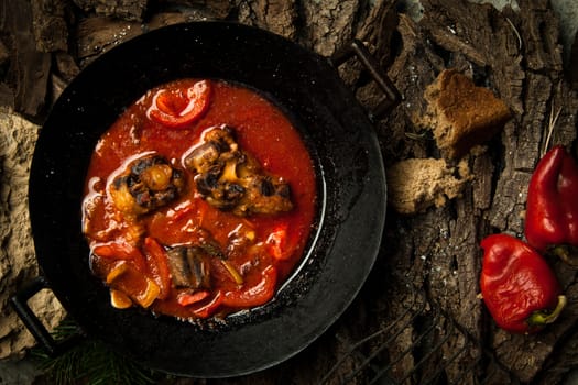 meat dish in a frying pan against the background of the bark of a tree