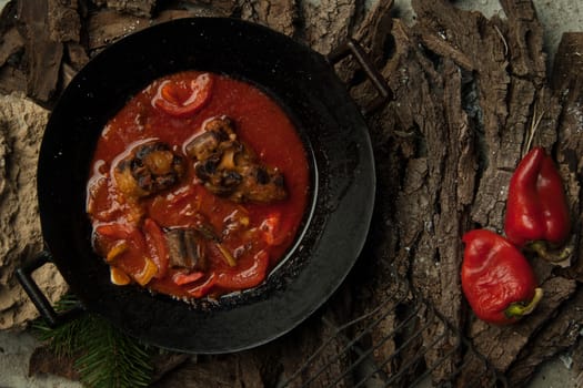 meat dish in a frying pan against the background of the bark of a tree