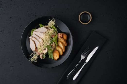 a dish of chicken on the black wooden surface, top view