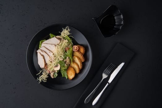 a dish of chicken on the black wooden surface, top view