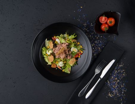 a dish of boiled meat on a black wooden surface, top view