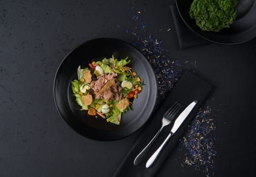 a dish of boiled meat on a black wooden surface, top view