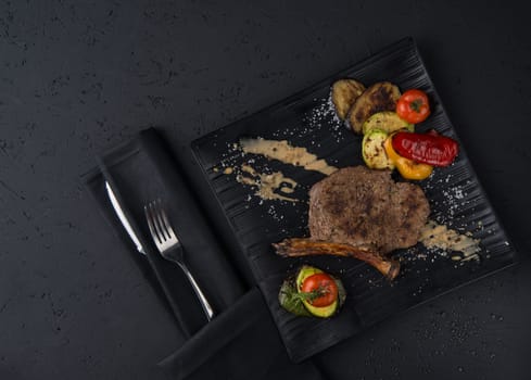 a dish of grilled meat on the black wooden surface, top view